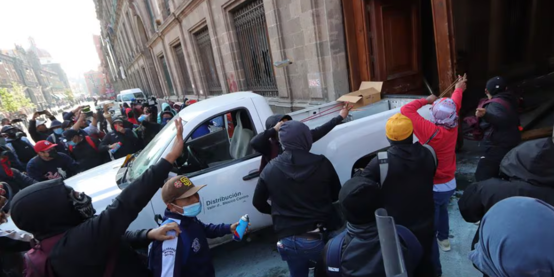 Normalistas de Ayotzinapa derriban una de las puertas del Palacio Nacional para presionar a López Obrador